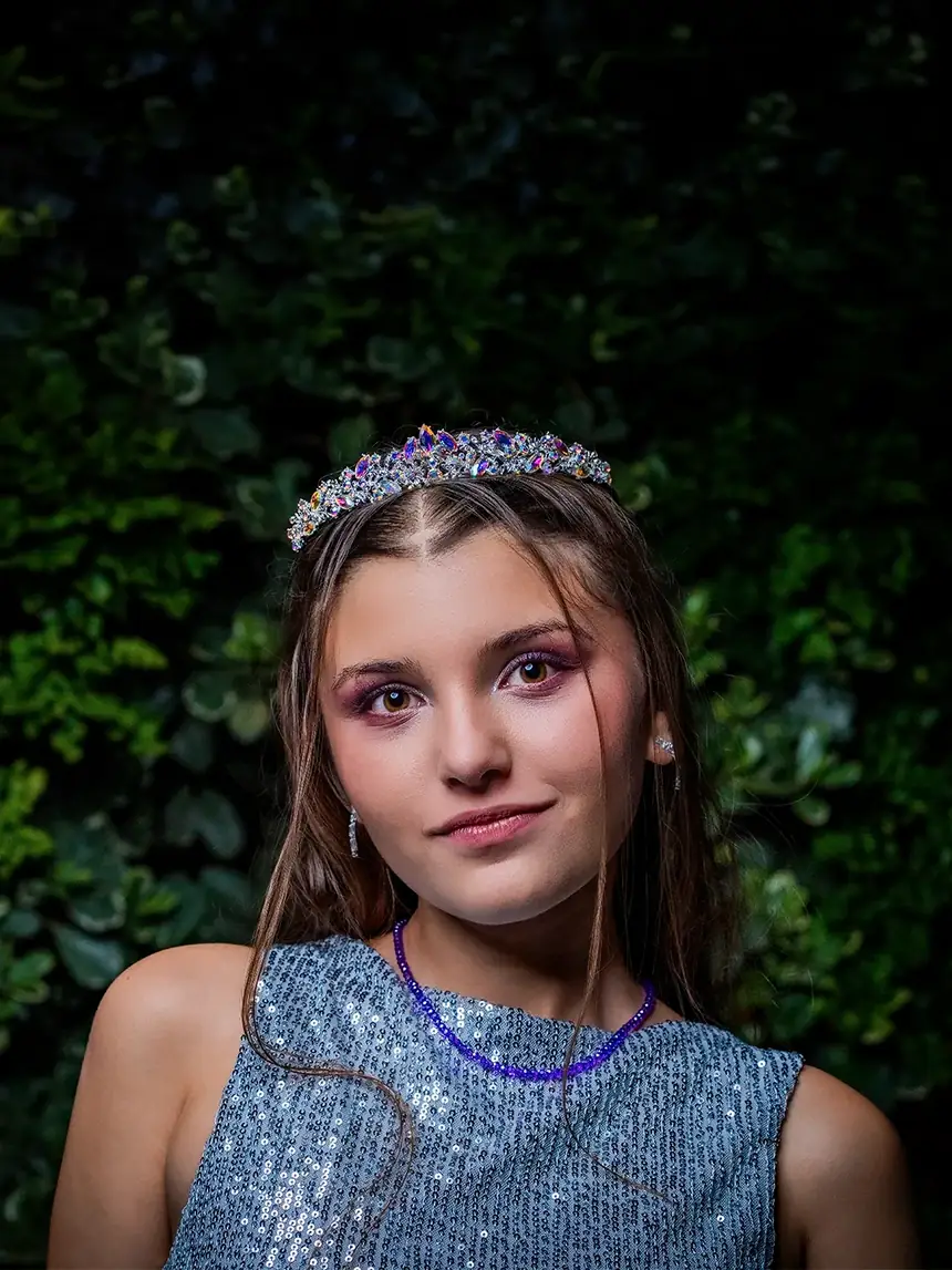 Retrato de una quinceañera con tiara, sobre un fondo de hojas