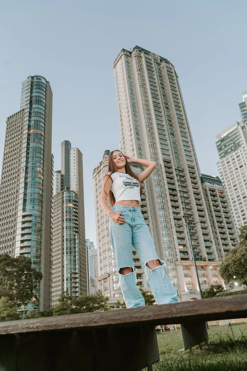 Quinceañera posando entre edificios altos en un día soleado