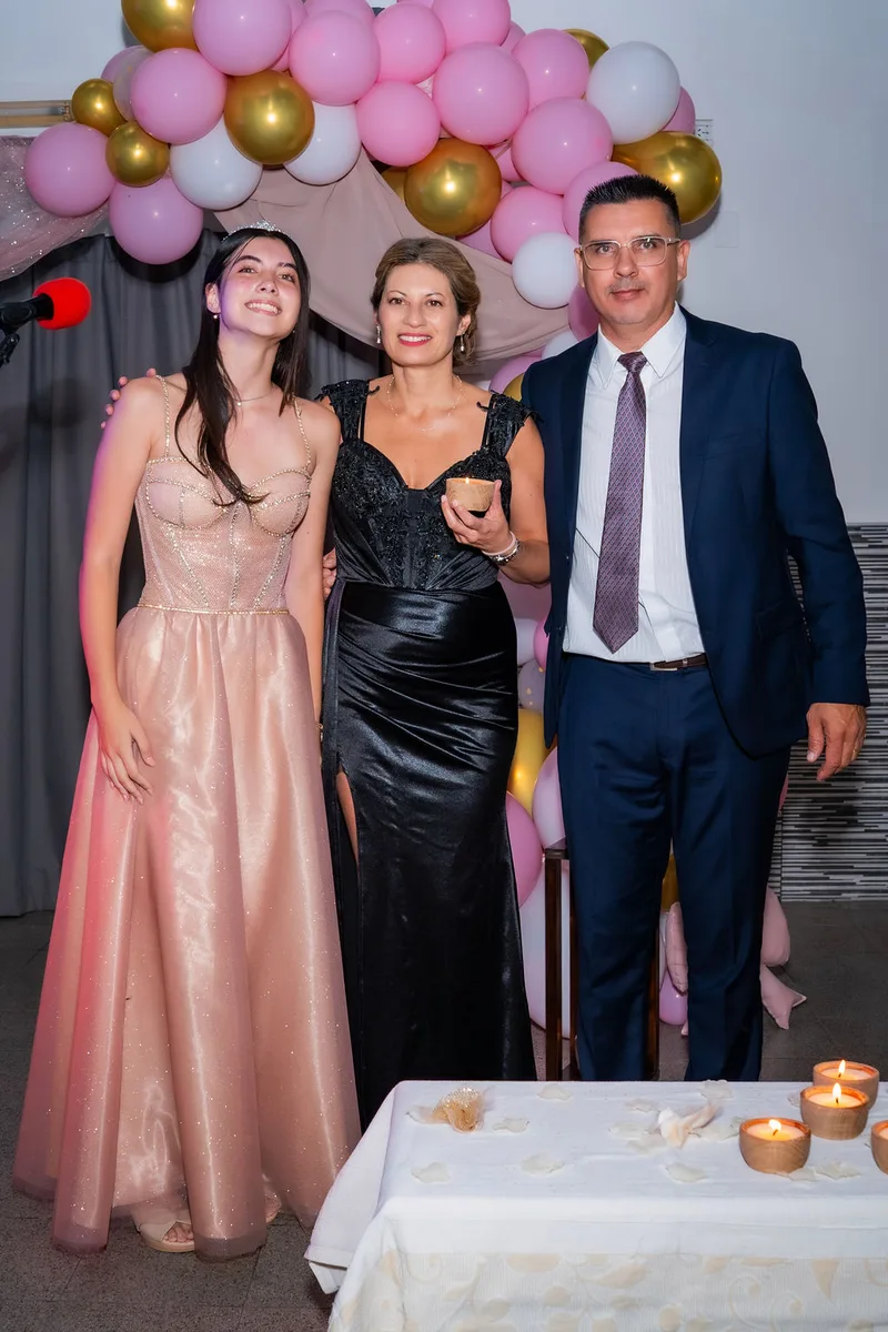 La quinceañera con sus papás junto a la mesa de las velas